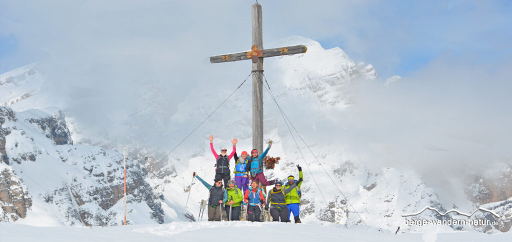 Schneeschuhwandergruppe vor Gipfelkreuz des Strudelkopfs